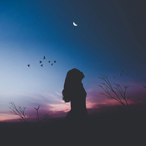 Silhouette of a woman from the side over a dark sky background